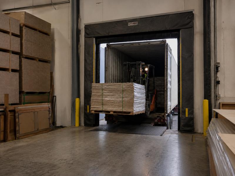 Forklift unloading panels from a container at a dock